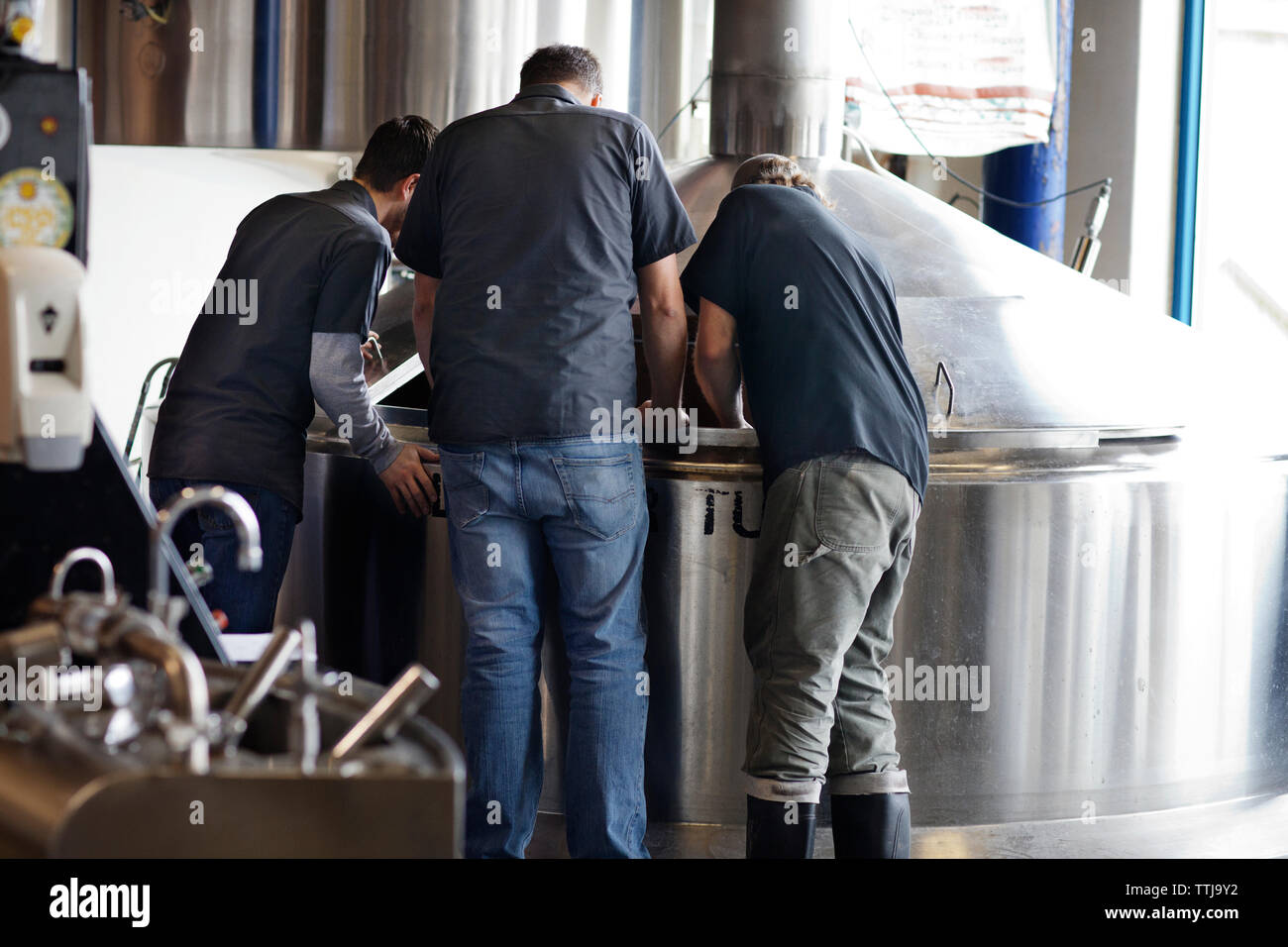 Rückansicht der Männer an Lagertank in Brauerei arbeiten Stockfoto