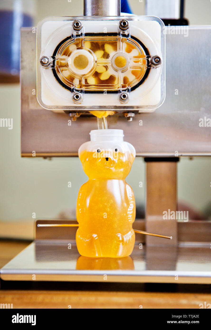 Honig wird in der Flasche mit Maschinen gegossen Stockfoto
