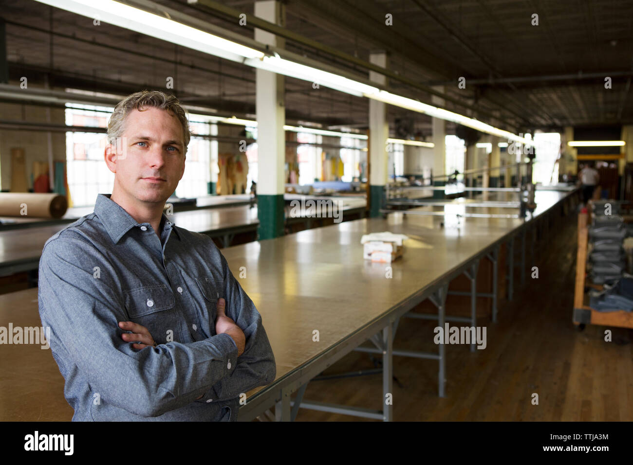 Portrait von Geschäftsmann steht die Tabelle in der Factory Stockfoto