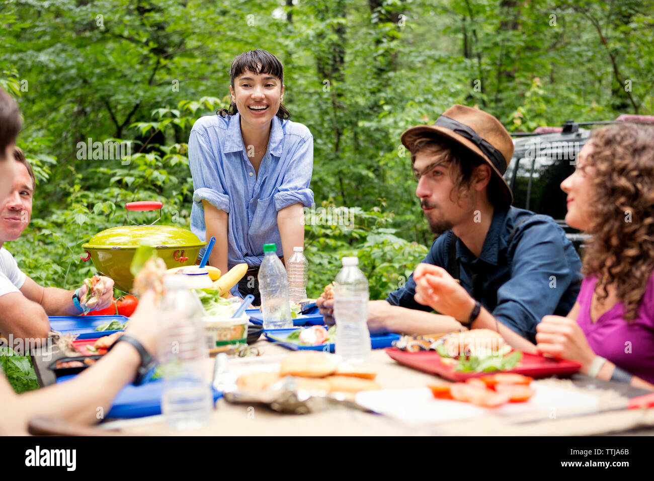 Frau suchen Freunde in Essen am Tisch für Picknick im Wald Stockfoto