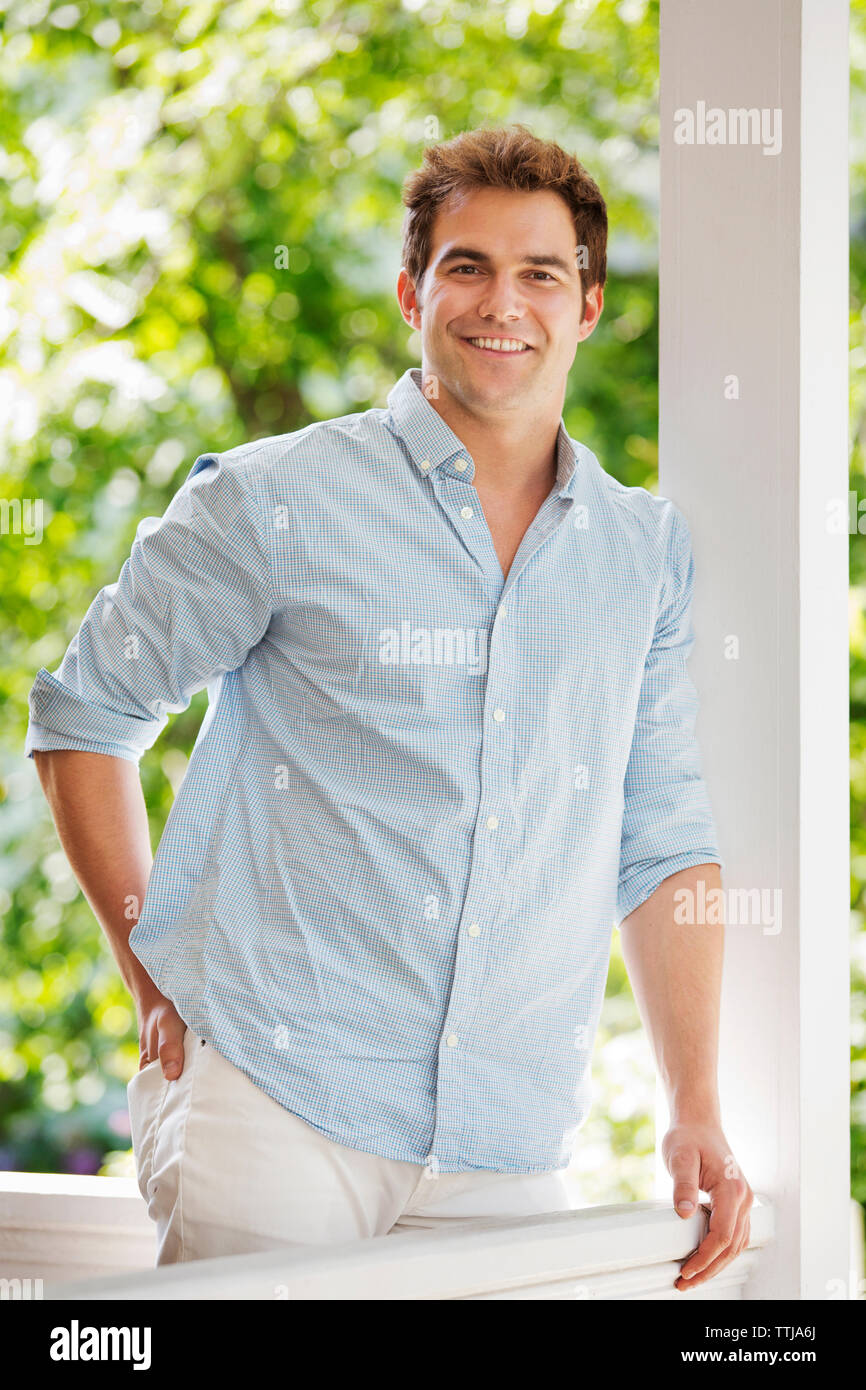 Porträt der Mann mit der Hand in der Tasche stehen durch Geländer an der Veranda Stockfoto