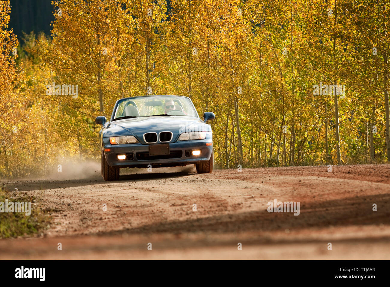 Mann fährt Auto auf unbefestigte Straße Stockfoto