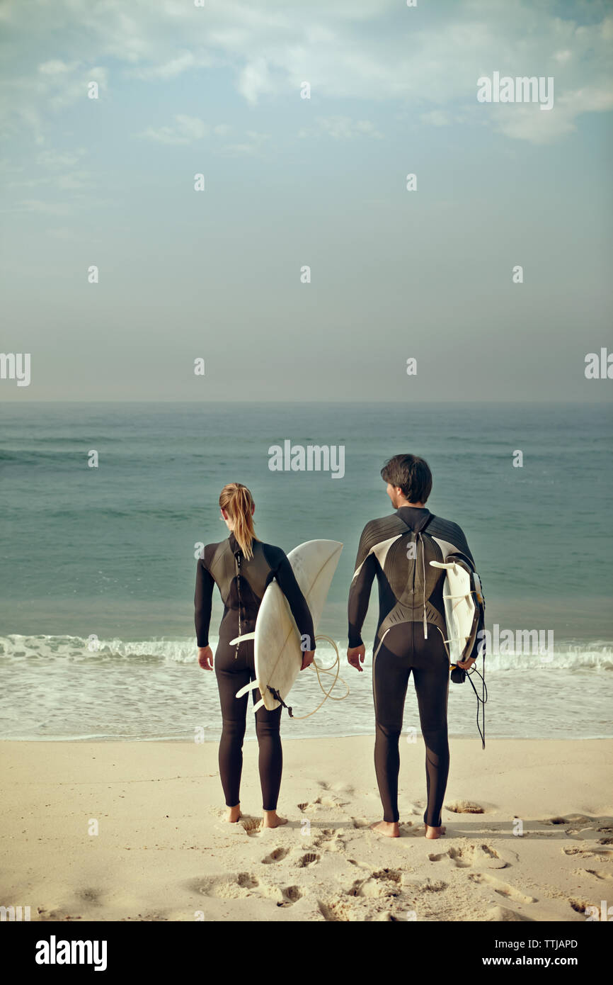 Ansicht der Rückseite des Paares, die surfbretter beim Stehen am Ufer Stockfoto