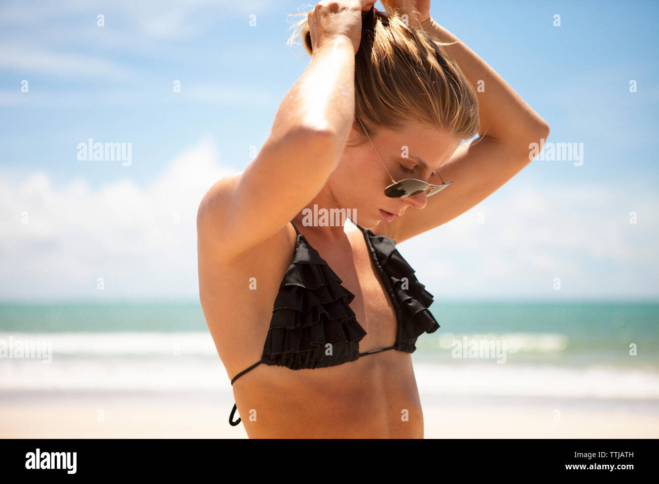 Frau im Bikini Top einstellen Haar am Strand Stockfoto