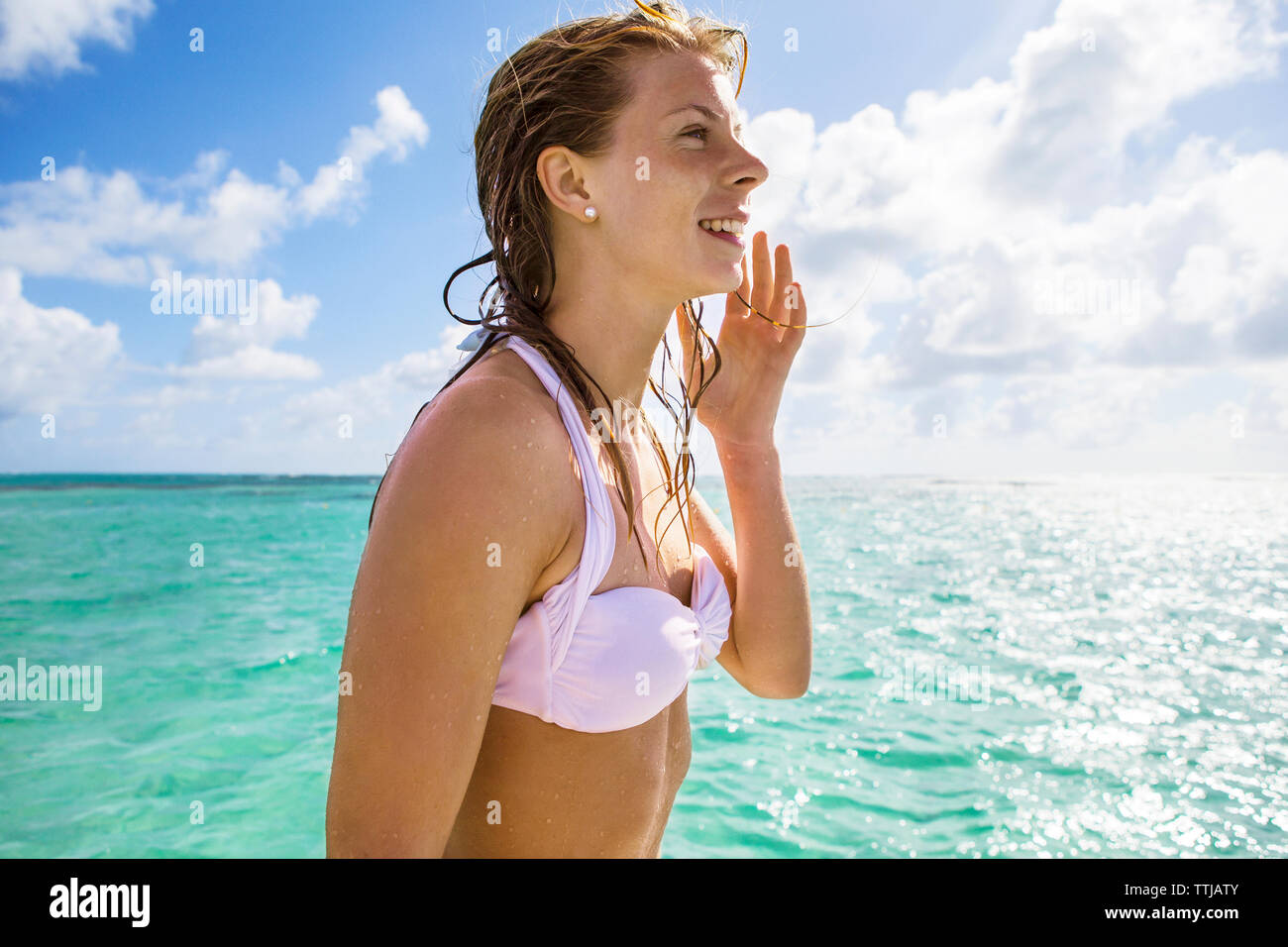 Glückliche Frau im Bikini Top gegen bewölkter Himmel Stockfoto
