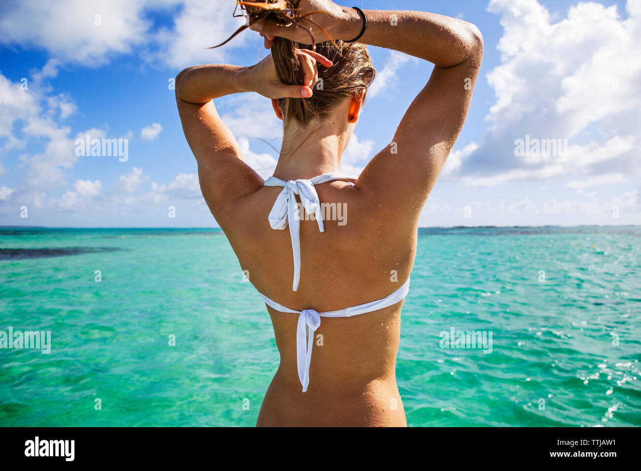 Ansicht der Rückseite Frau im Bikini Top einstellen Haar beim Stehen in der Meer gegen bewölkter Himmel Stockfoto