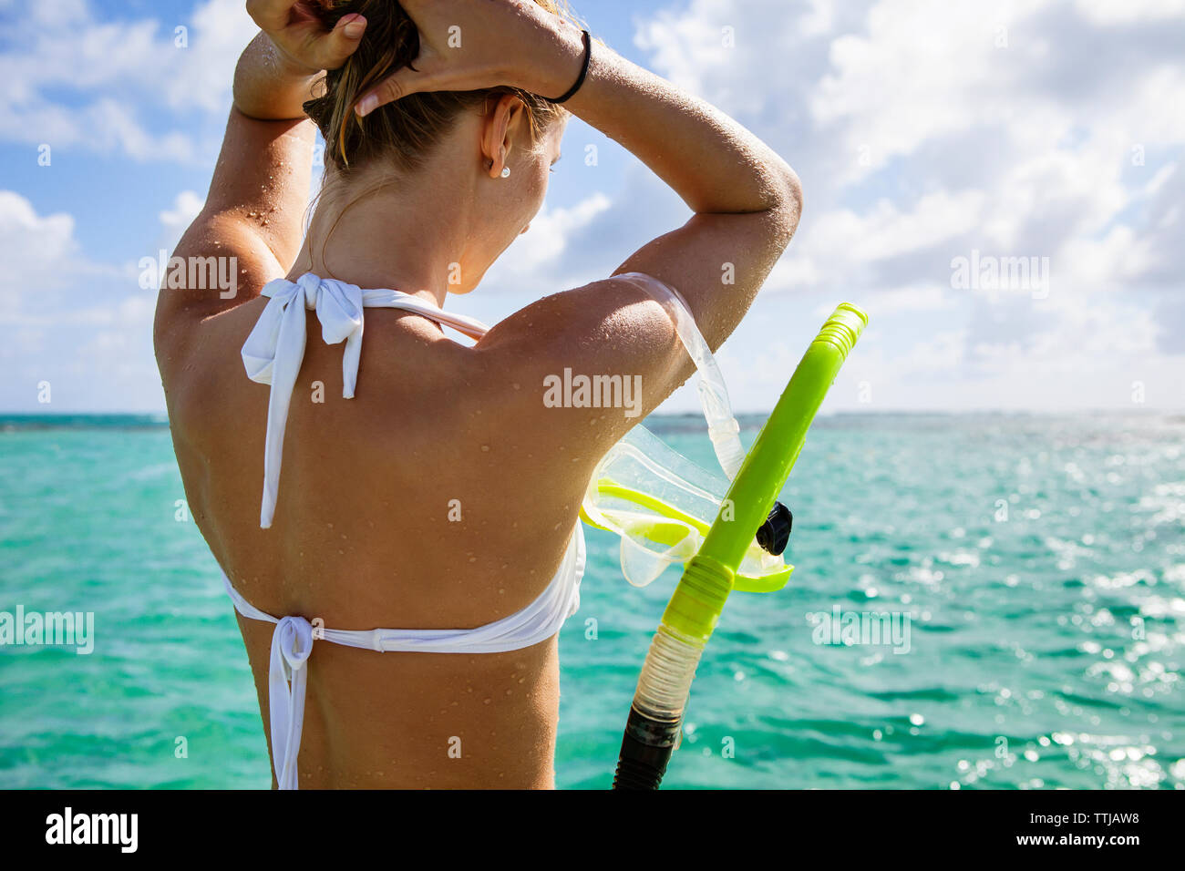 Frau mit Schnorchel einstellen Haar beim Stehen in der Meer Stockfoto
