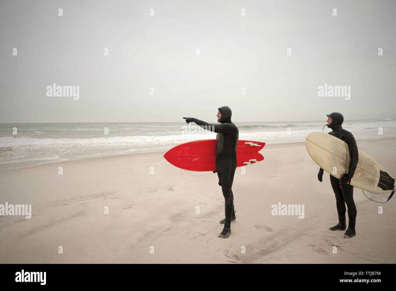 Freunde in Neoprenanzüge am Strand stehen Stockfoto