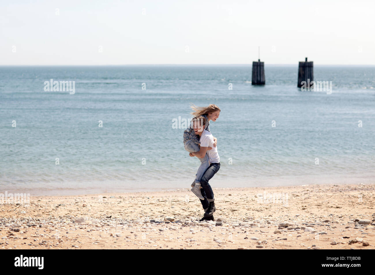 Mann anheben Freundin beim Stehen auf Shore Beach Stockfoto