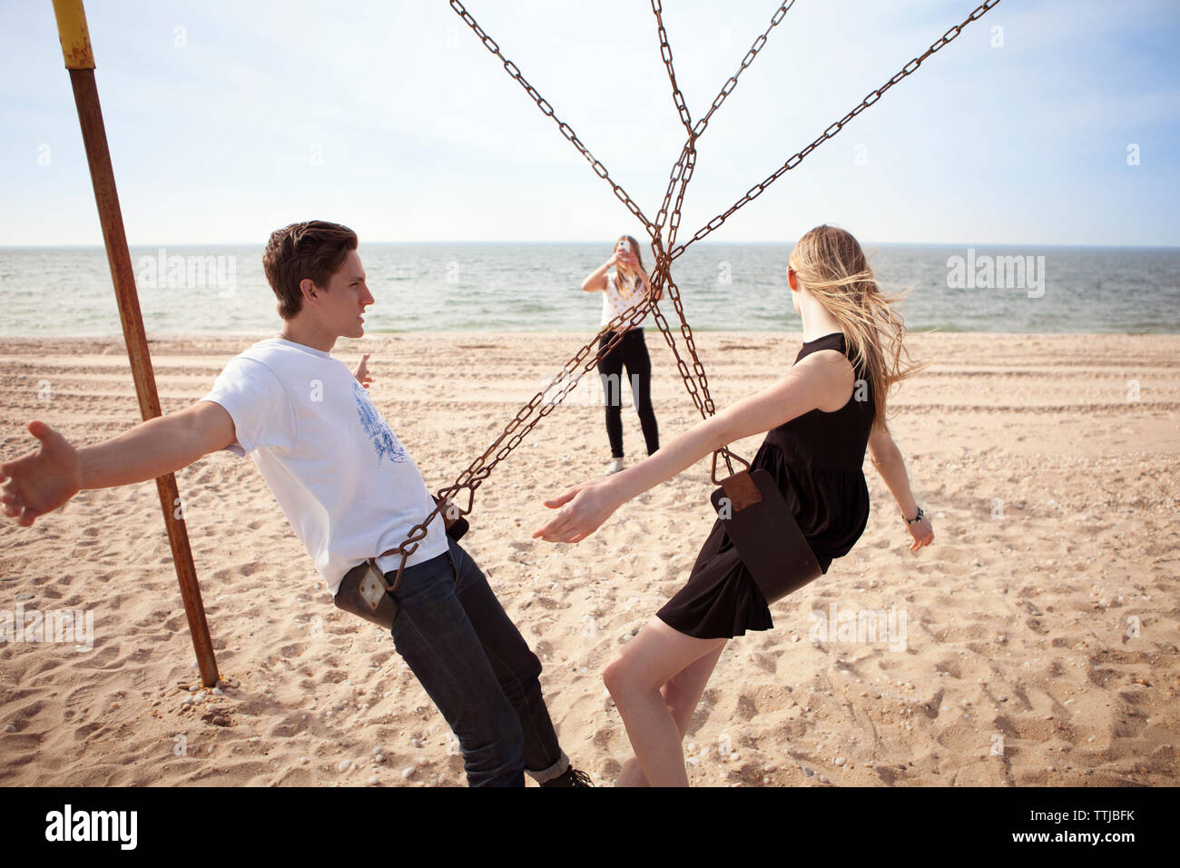 Frau fotografieren Freunde auf Schwingen am Strand Stockfoto