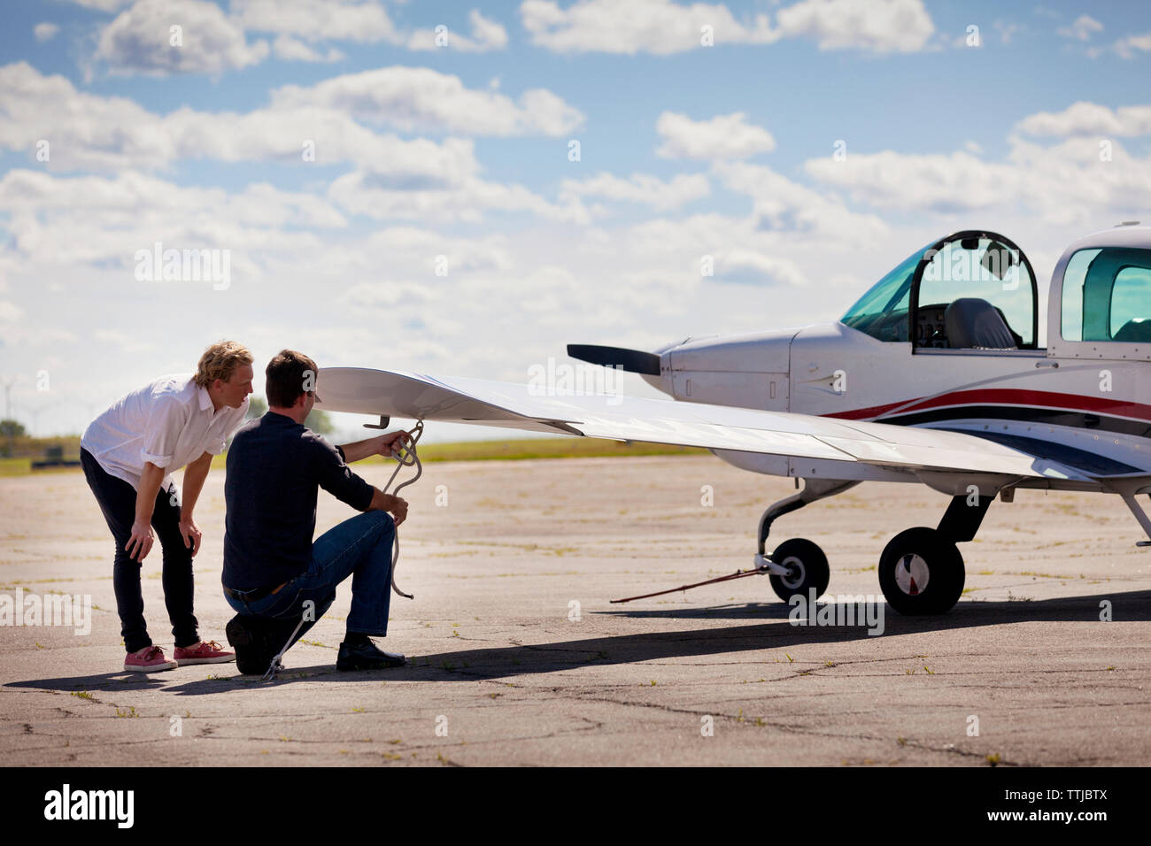 Mechanik reparieren Flugzeugflügel am Flugplatz gegen bewölkter Himmel Stockfoto