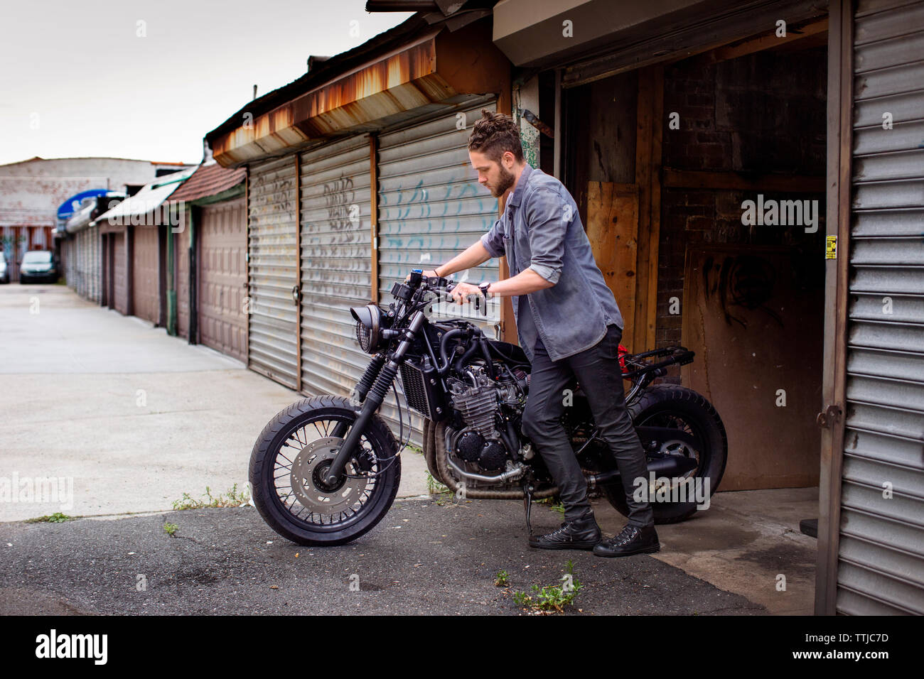 Mann Motorrad Drücken außerhalb der Werkstatt Stockfoto