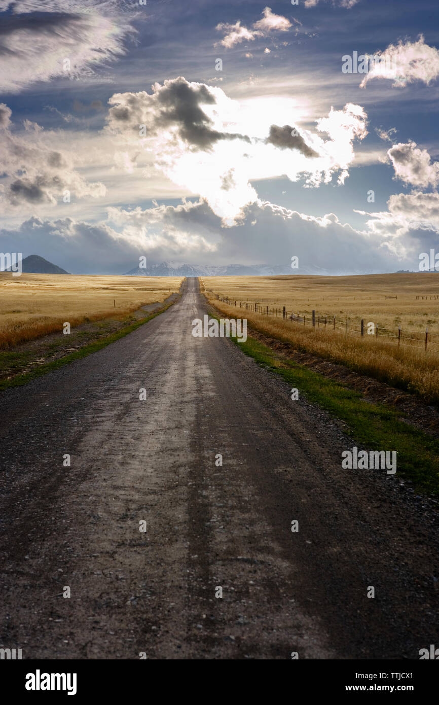 Straße inmitten von Feld gegen bewölkter Himmel Stockfoto