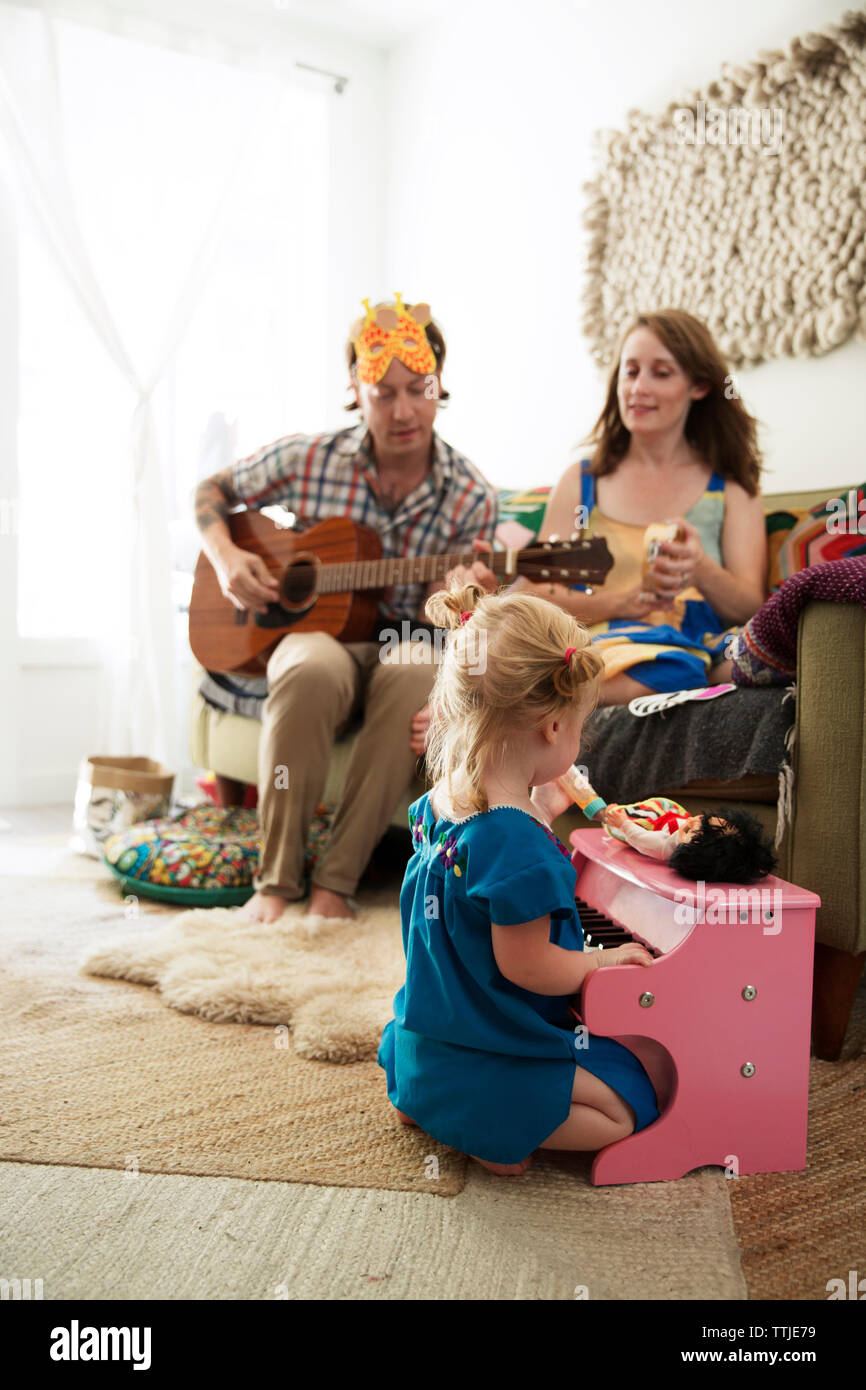 Tochter Klavier spielen, während die Eltern sitzen auf dem Sofa zu Hause Stockfoto