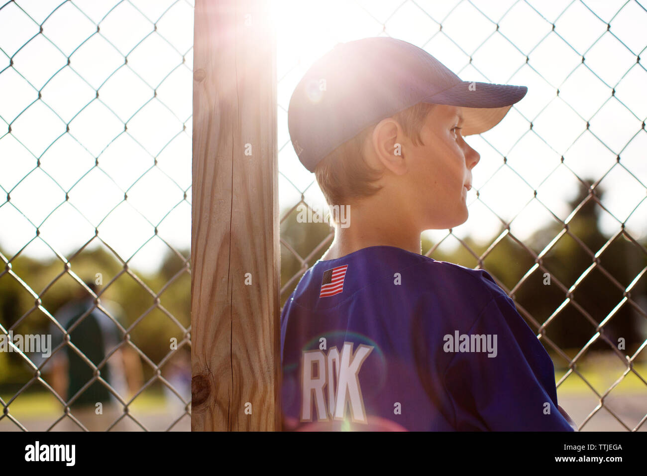 Baseball player weg schauen beim Stehen durch Zaun Stockfoto