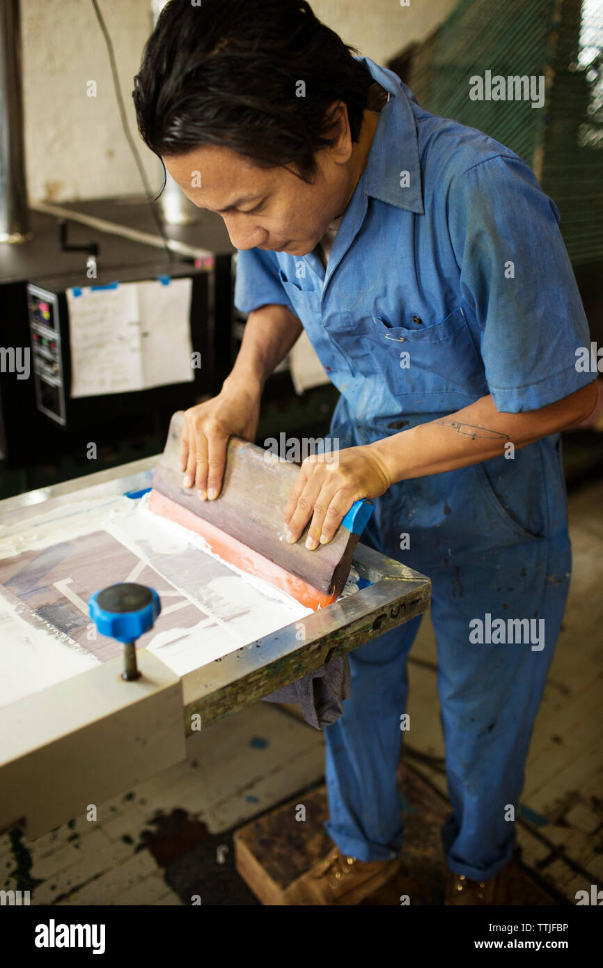 Hohe Betrachtungswinkel und der Mann sie Tinte auf Frame in der Werkstatt Stockfoto