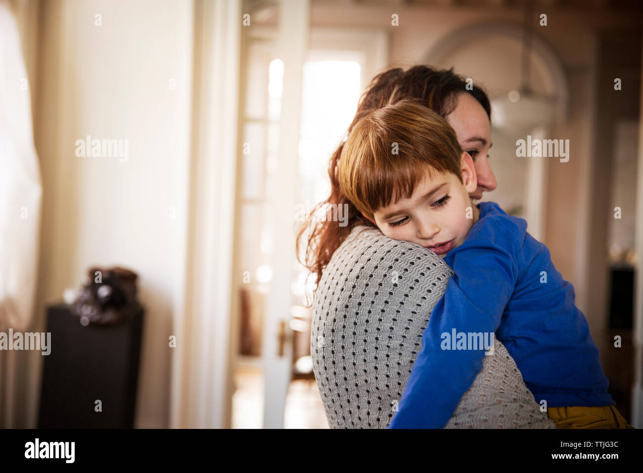 Frau, die Sohn während zu Hause stehend Stockfoto