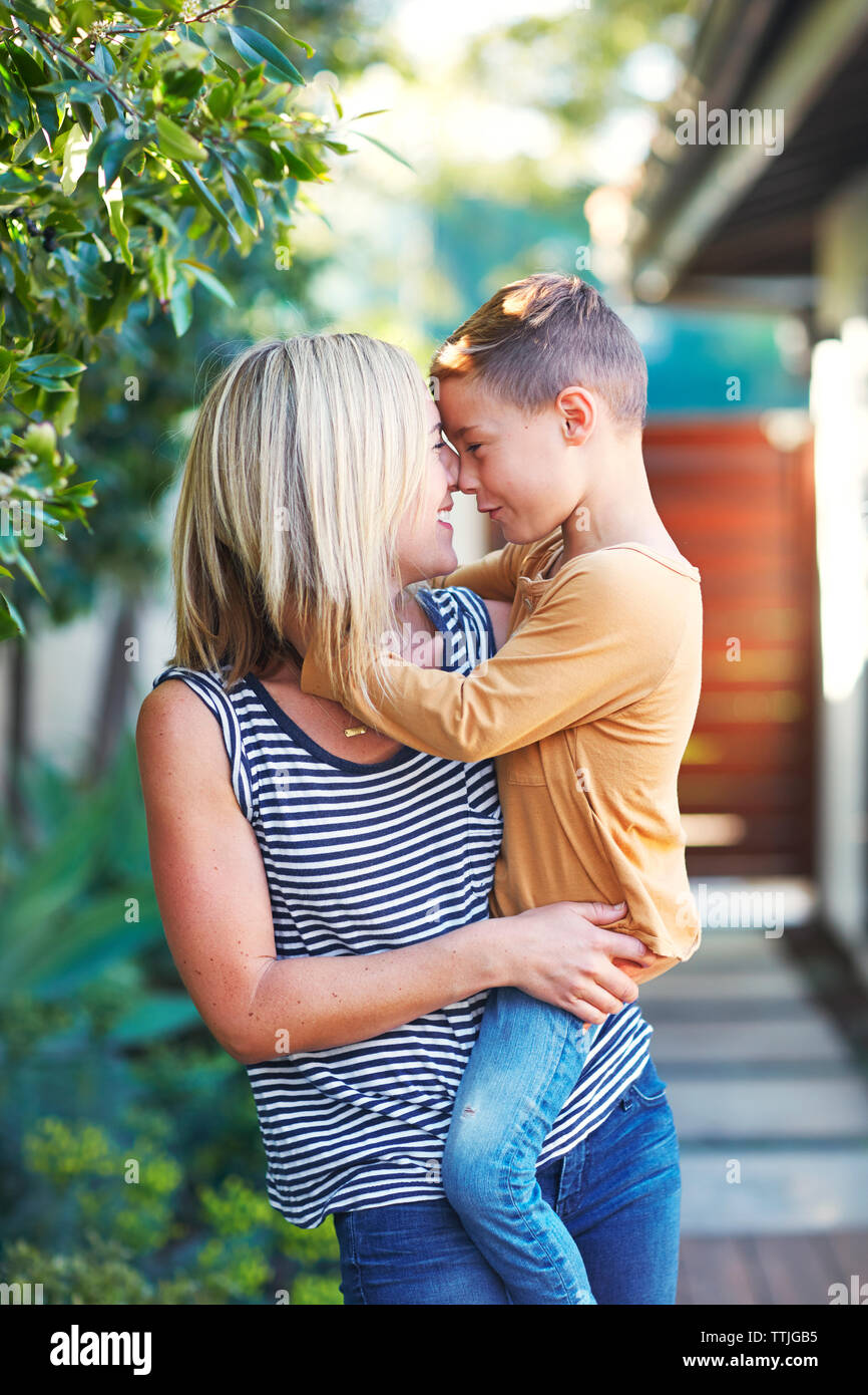 Mutter Reiben der Nase mit Sohn beim Stehen im Hinterhof Stockfoto