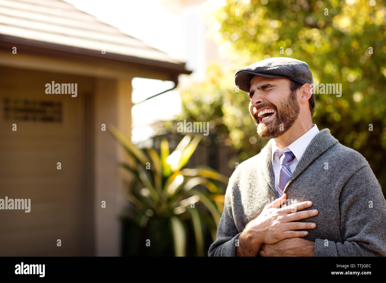 Fröhlicher Mann lachend, während im Hinterhof stand Stockfoto