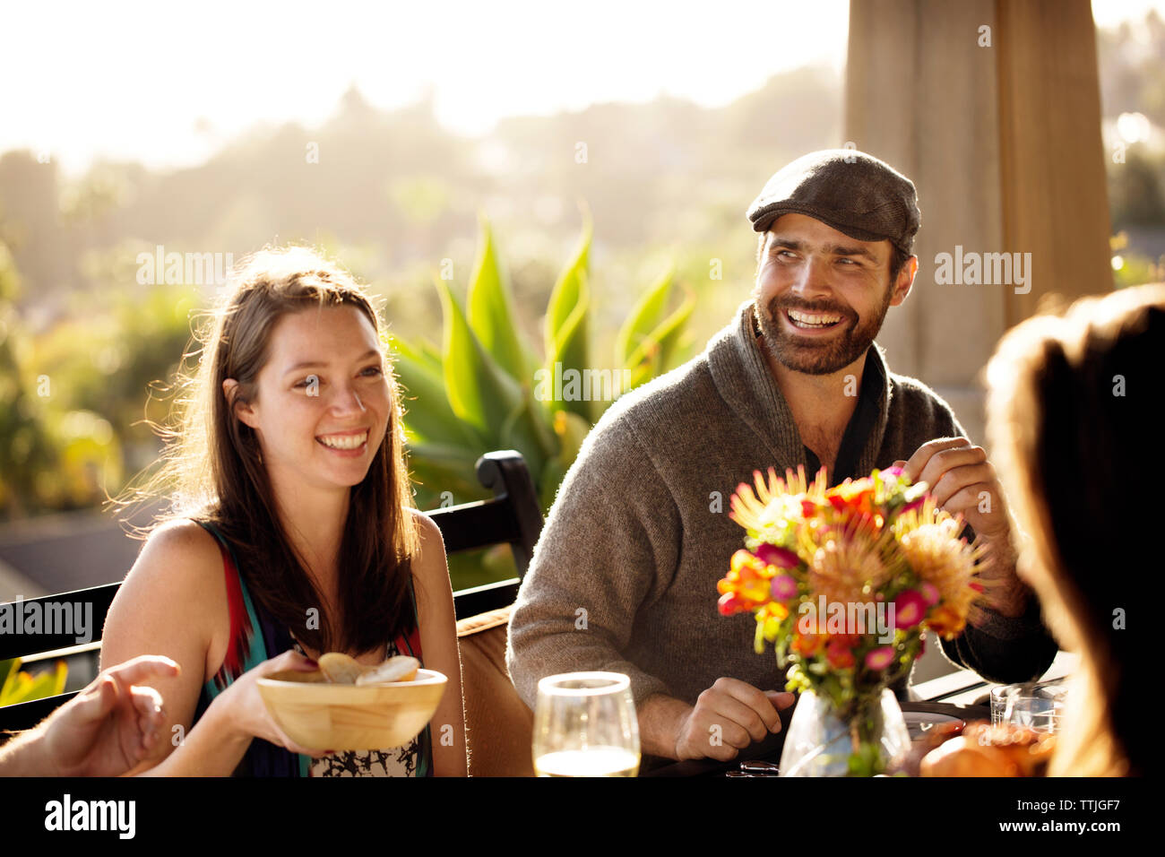 Glückliche Menschen Wegschauen beim Sitzen mit Frau am Esstisch Stockfoto