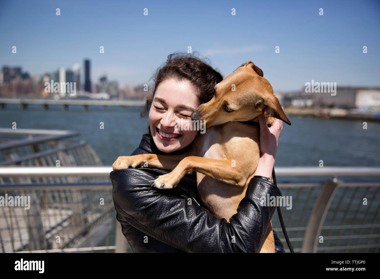 Glückliche Frau umarmt Hund während auf Steg gegen Sky standing Stockfoto