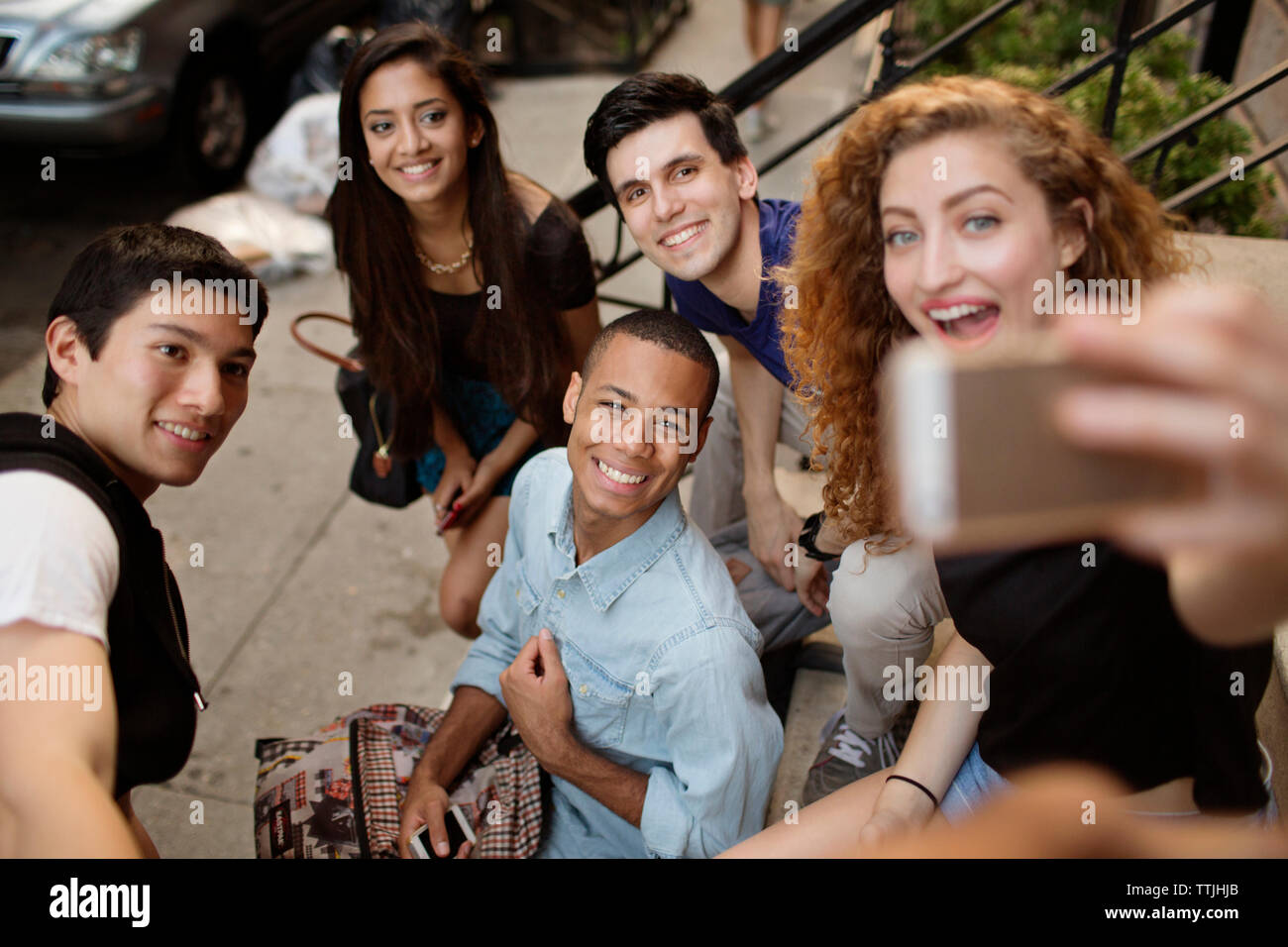 Hohe Betrachtungswinkel der Frau unter selfie mit Freunden beim Sitzen auf Schritte Stockfoto