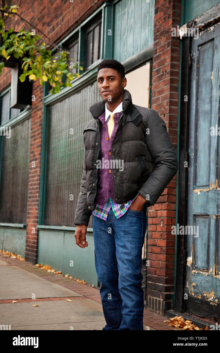 Porträt der Mann mit der Hand in der Tasche stehen auf Fußweg gegen Gebäude Stockfoto