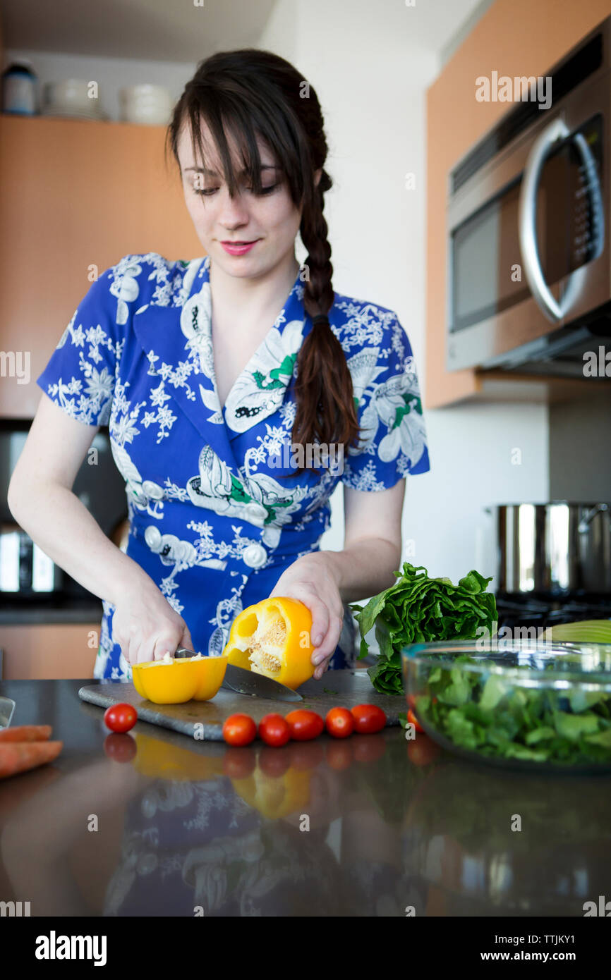 Frau schneiden gelbe Paprika beim Stehen in der Küche zu Hause Stockfoto