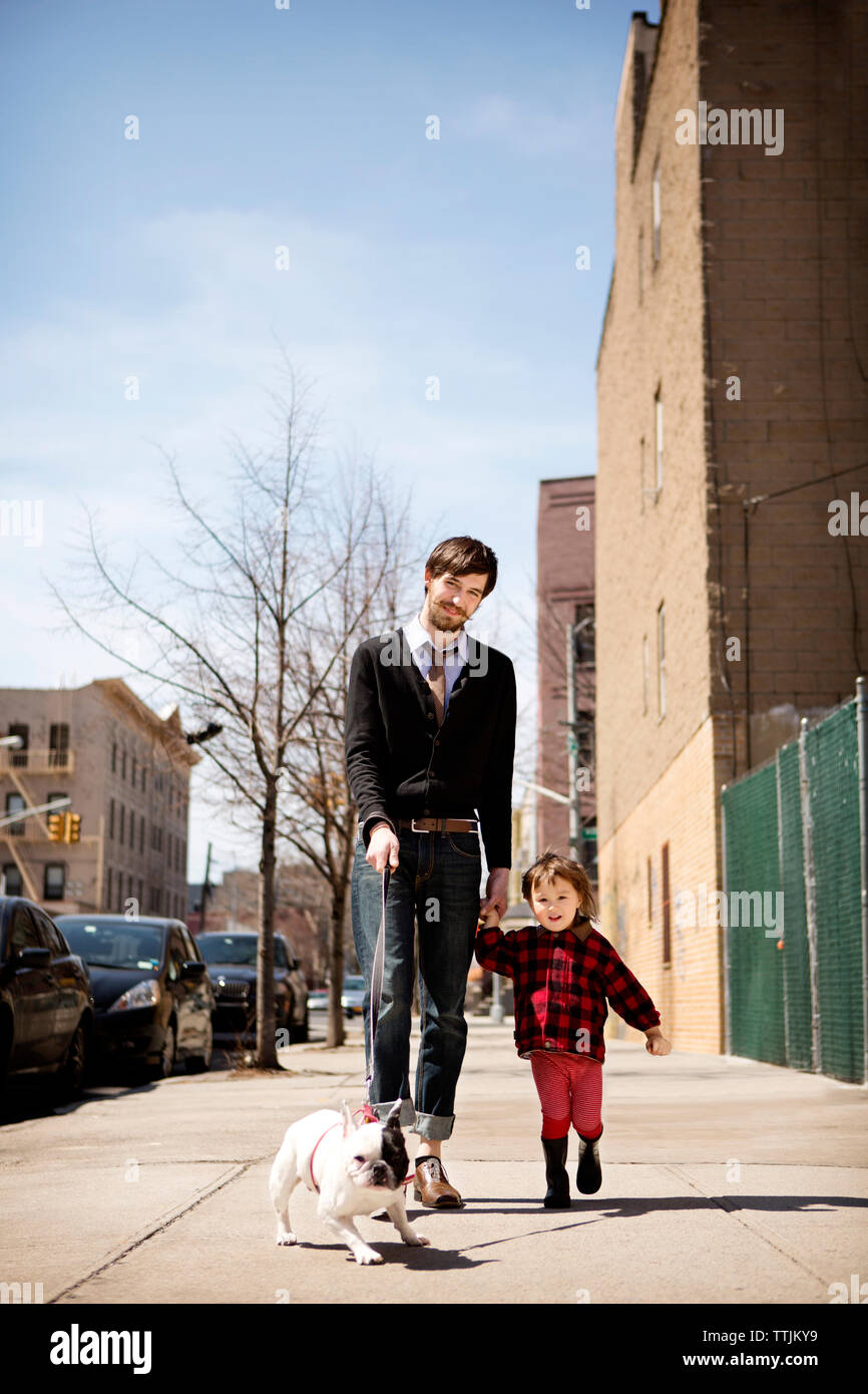 Portrait von der Hand des Vaters Holding Tochter beim Wandern mit Hund auf Fußweg Stockfoto