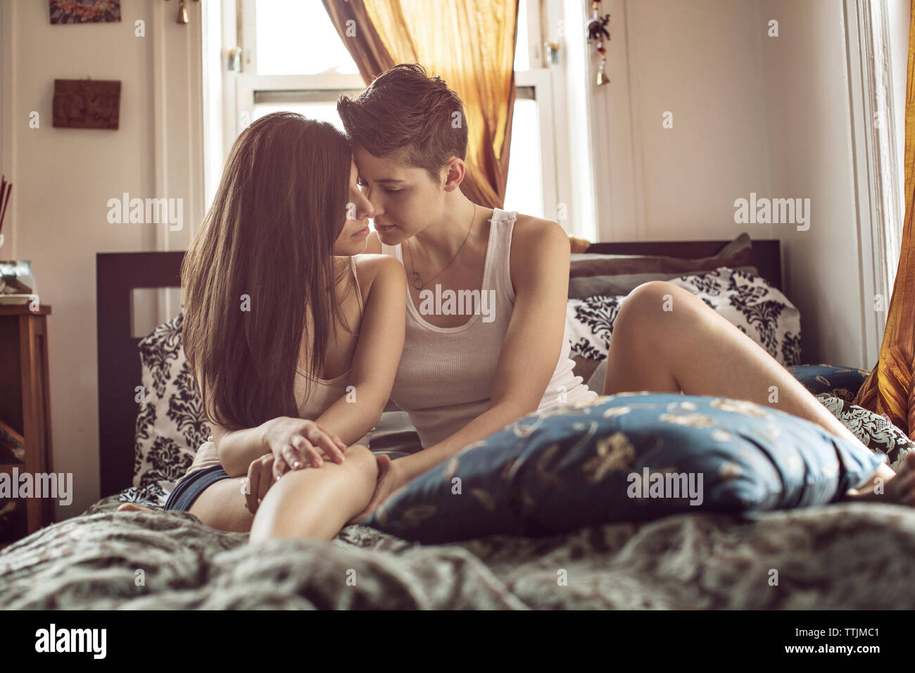 Zärtliche Lesben auf dem Bett zu Hause sitzen Stockfoto