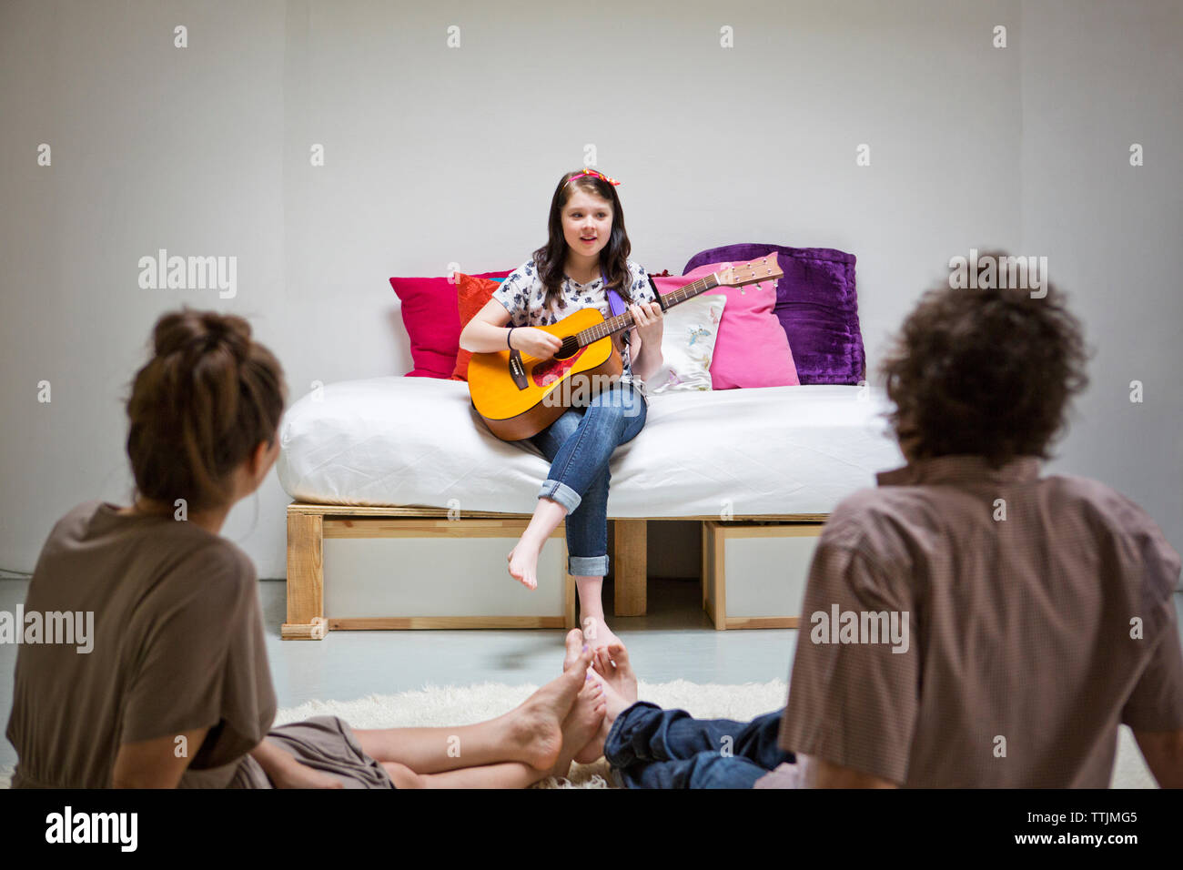 Mädchen, Eltern, während Gitarre spielen Stockfoto