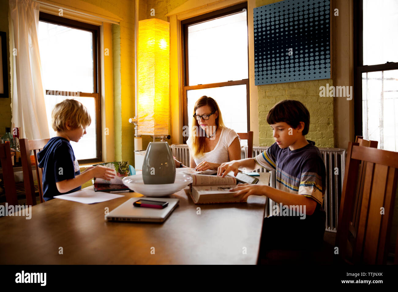 Die Mutter sitzt mit Söhnen Hausaufgaben am Tisch Stockfoto