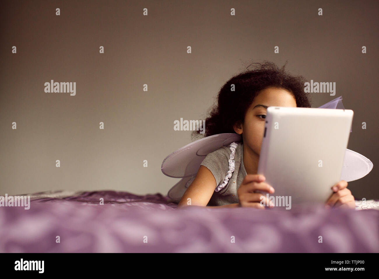 Mädchen in Fairy wings mit Tablet-PC beim liegen auf dem Bett Stockfoto