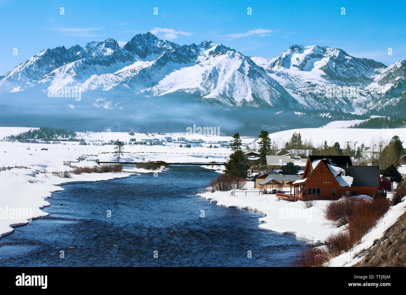 Blick auf die Häuser am Feld gegen schneebedeckte Berge Stockfoto