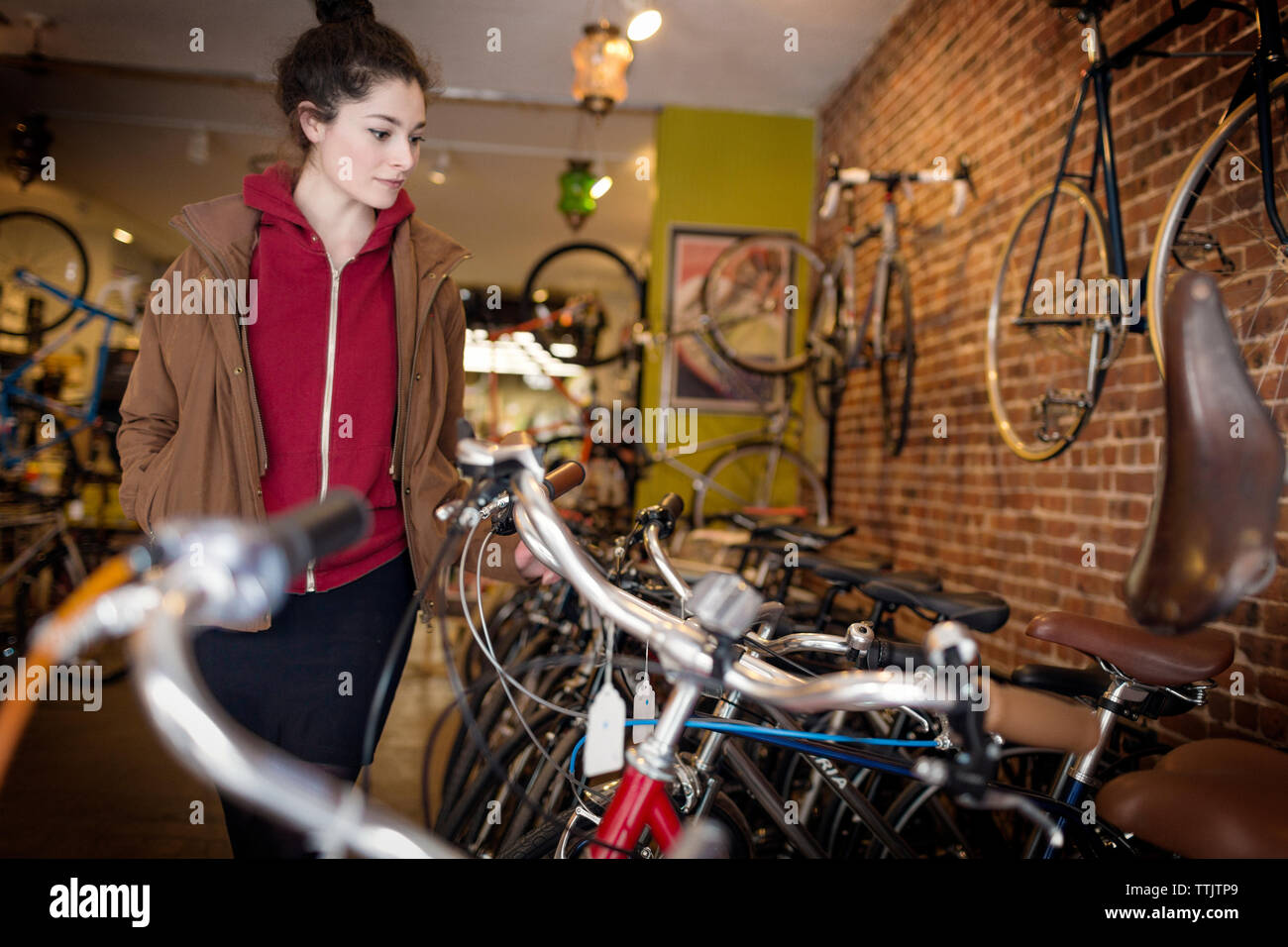 Frau mit Händen in den Taschen am Fahrrad, beim Stehen in Store Stockfoto