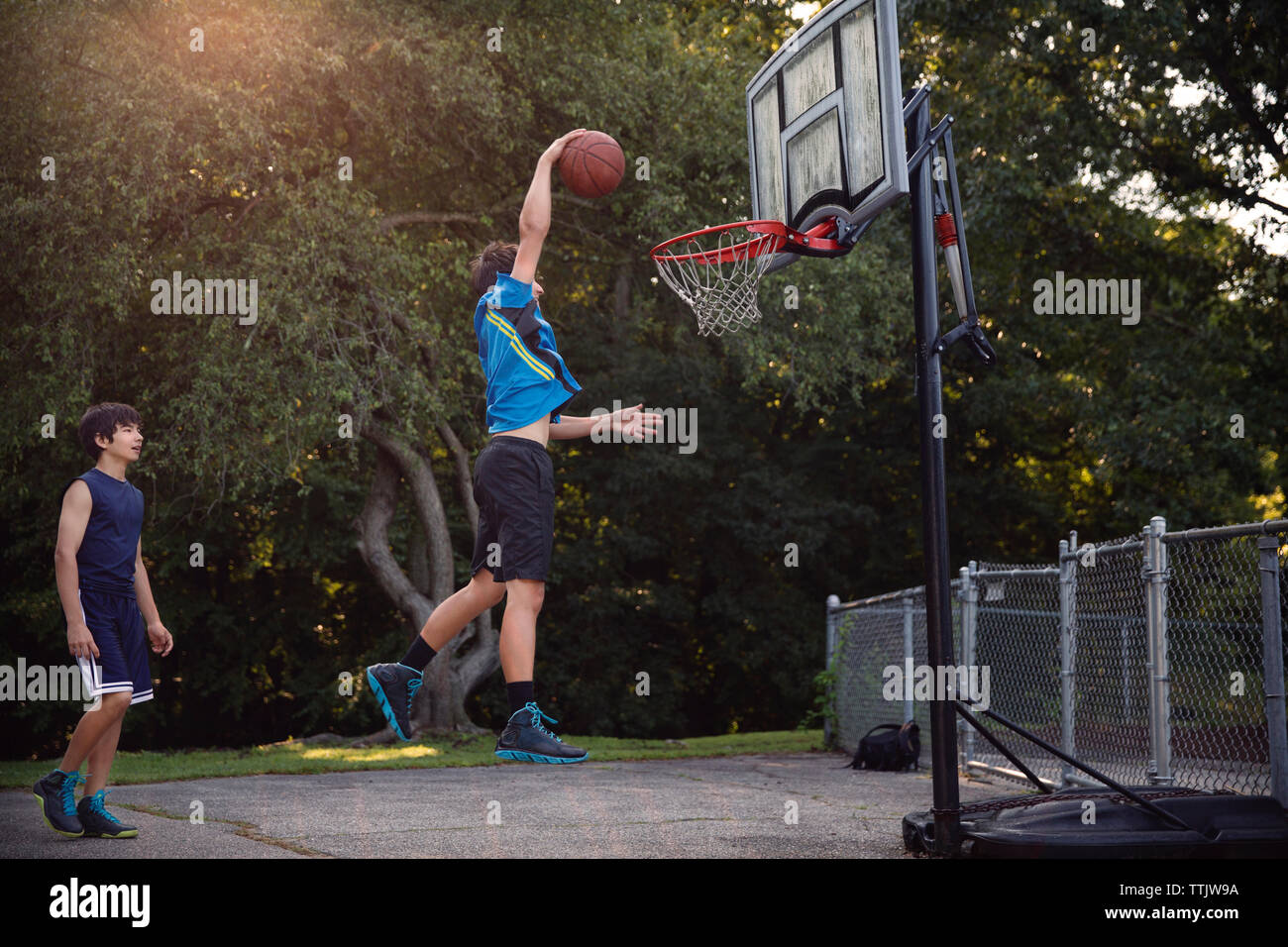 Spieler Basketball spielen am Hof von Bäumen Stockfoto