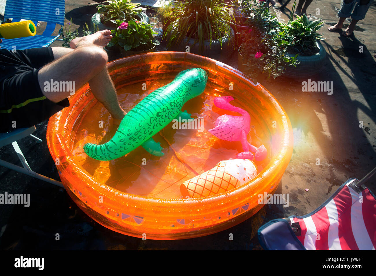 Zugeschnittenes Bild des Menschen durch Planschbecken im Garten Party an einem sonnigen Tag ruhen Stockfoto