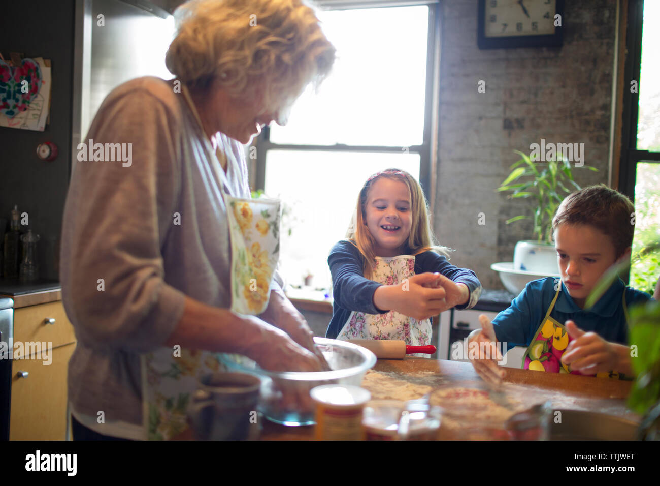 Glückliche Kinder mit Großmutter mischen Mehl in der Küche Stockfoto