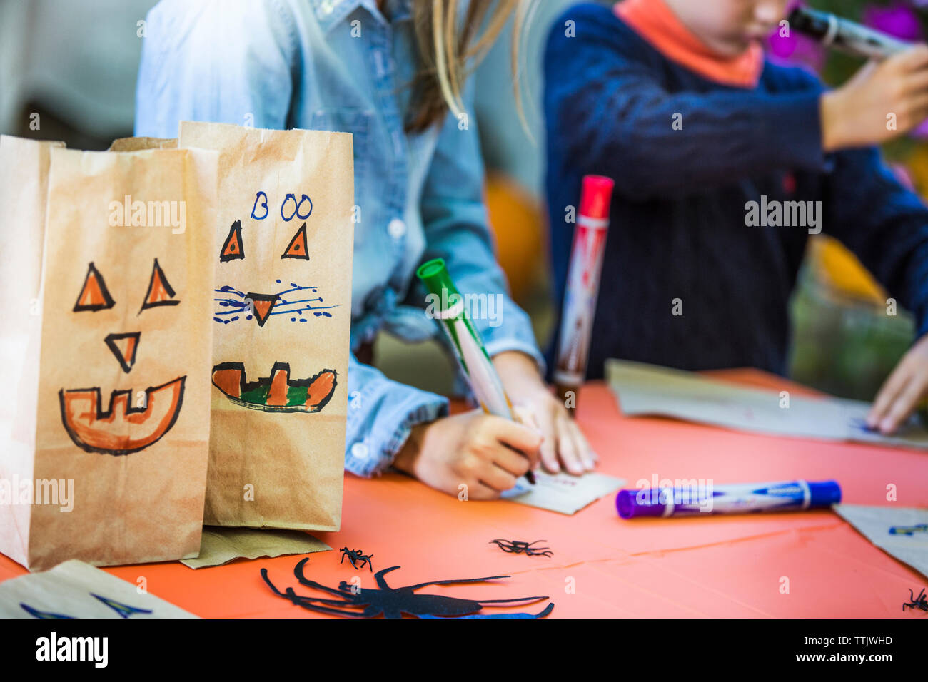 Die smiley-Gesichter, die auf dem Papier taschen von Geschwistern, Kunst am Tisch während der Halloween Party Stockfoto