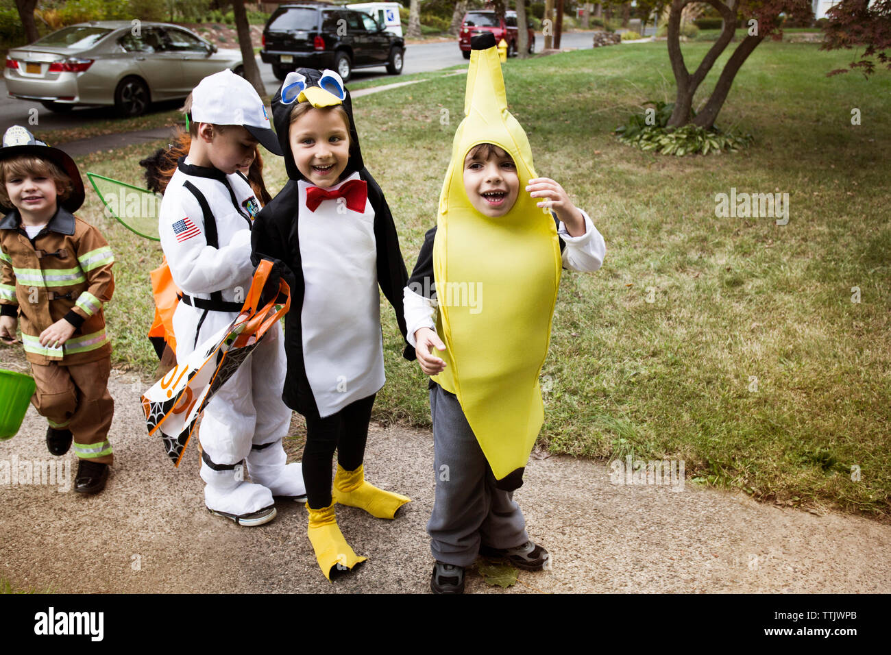 Fröhliche Kinder in Halloween Kostüme stehen auf Bahn während Süßes oder Saures Stockfoto