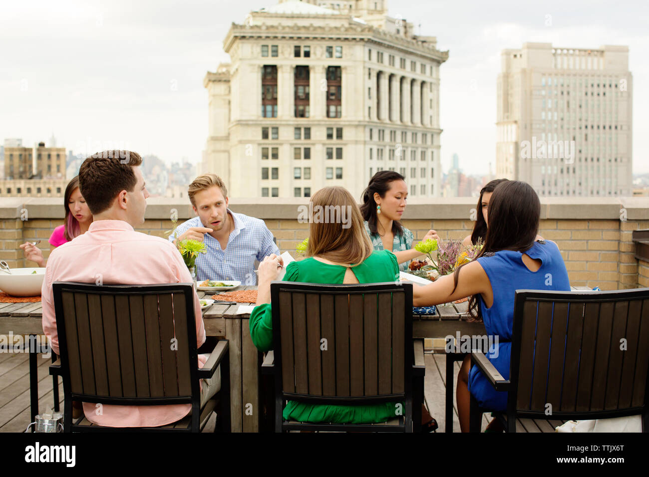 Freunde sprechen, während Sie Essen am Tisch auf der Terrasse des Stadt Stockfoto