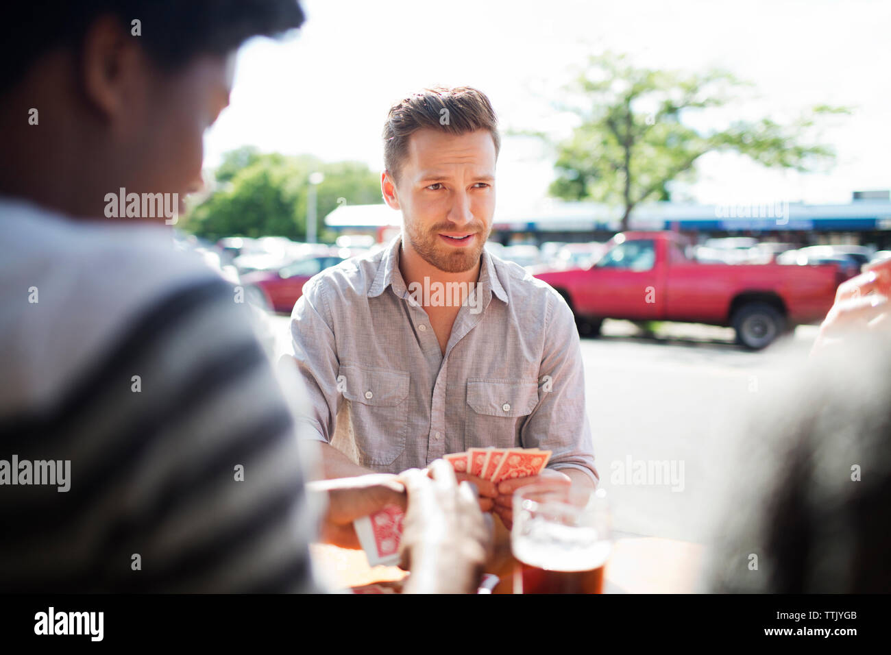 Der Mensch auf der Suche nach Freund beim Spielen Karten am Tisch gegen Fenster in der Brauerei Stockfoto