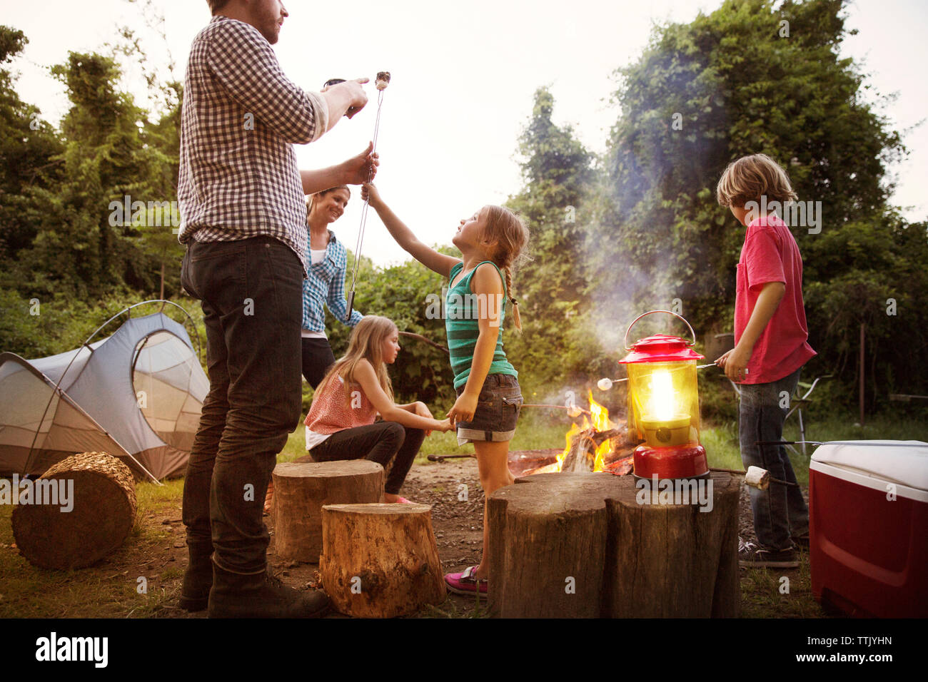 Tochter, geröstete Marshmallow zu Vater und genießen Sie mit der Familie im Sommer Camp Stockfoto