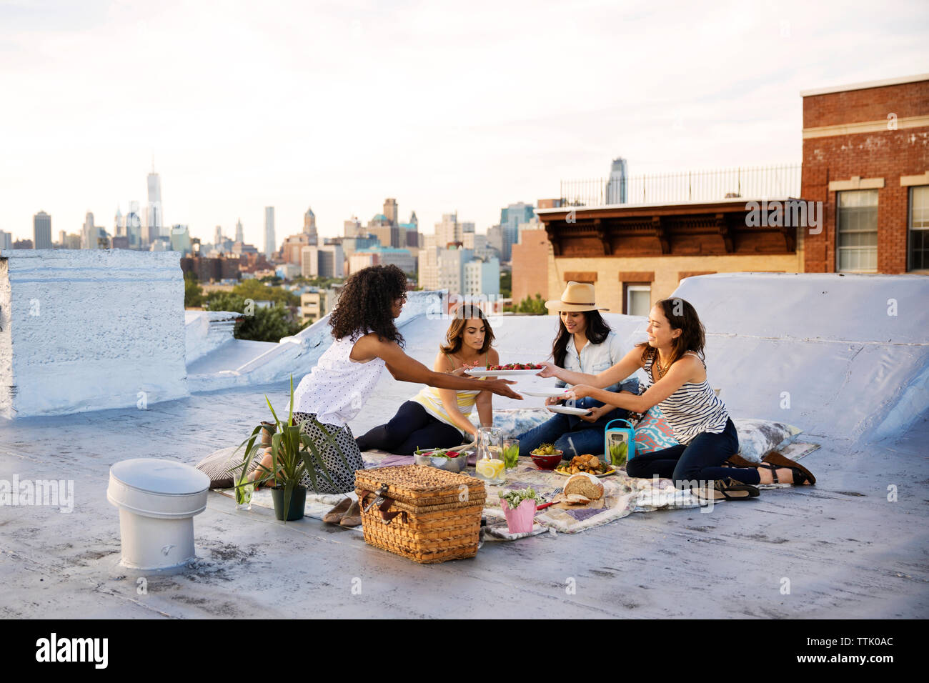 Freunde in Essen auf Gebäude Terrasse gegen Himmel während der Partei Stockfoto