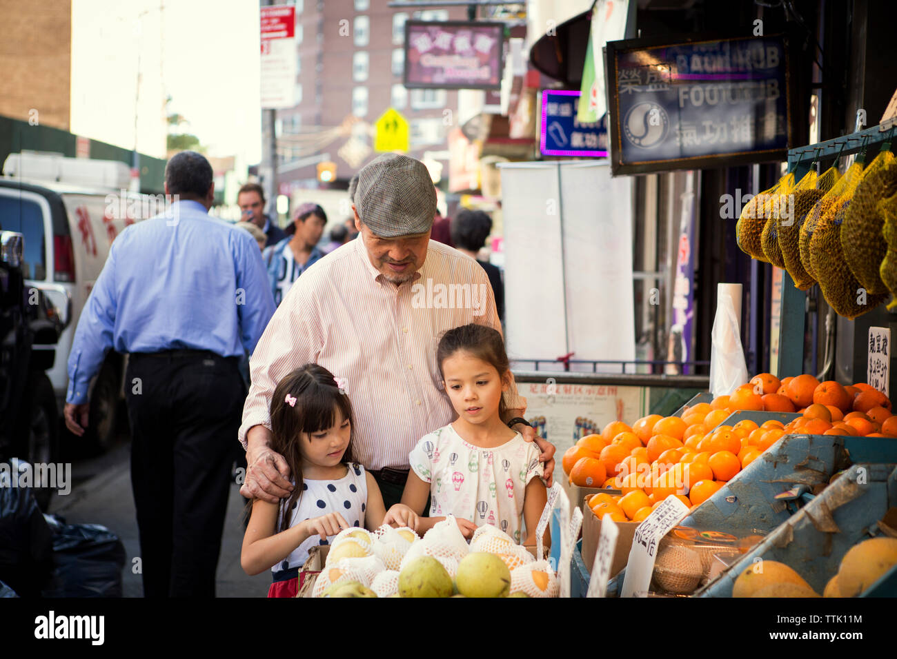 Großvater mit Enkelinnen bei Obst in Marktstand Stockfoto