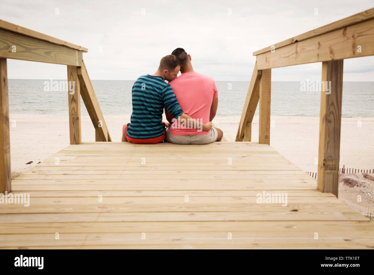 Ansicht der Rückseite des homosexuelle Paare sitzen auf der Promenade vor der See Stockfoto