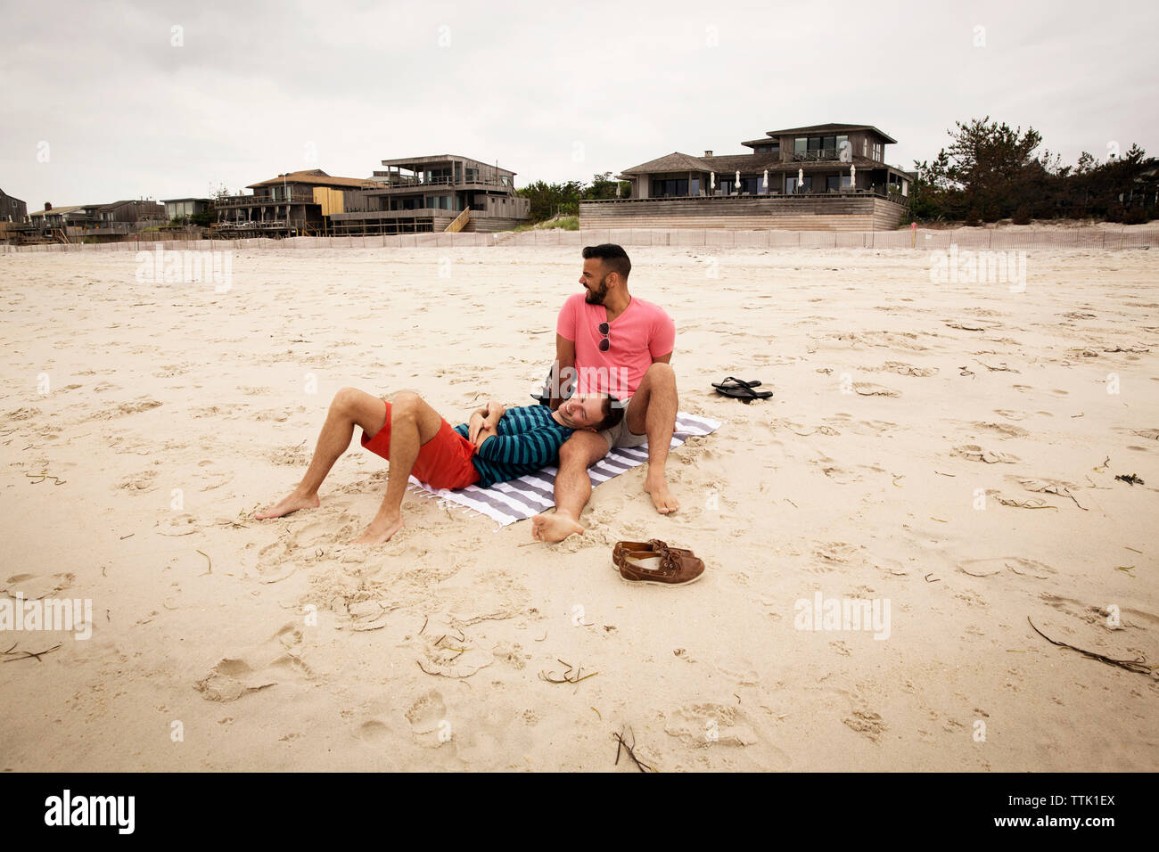 Glücklich homosexuelle Paare ausruhen am Strand gegen Sky Stockfoto