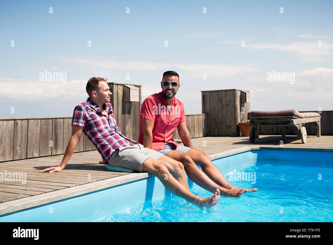 Homosexuelle Paare Ausruhen am Pool gegen Sky Stockfoto