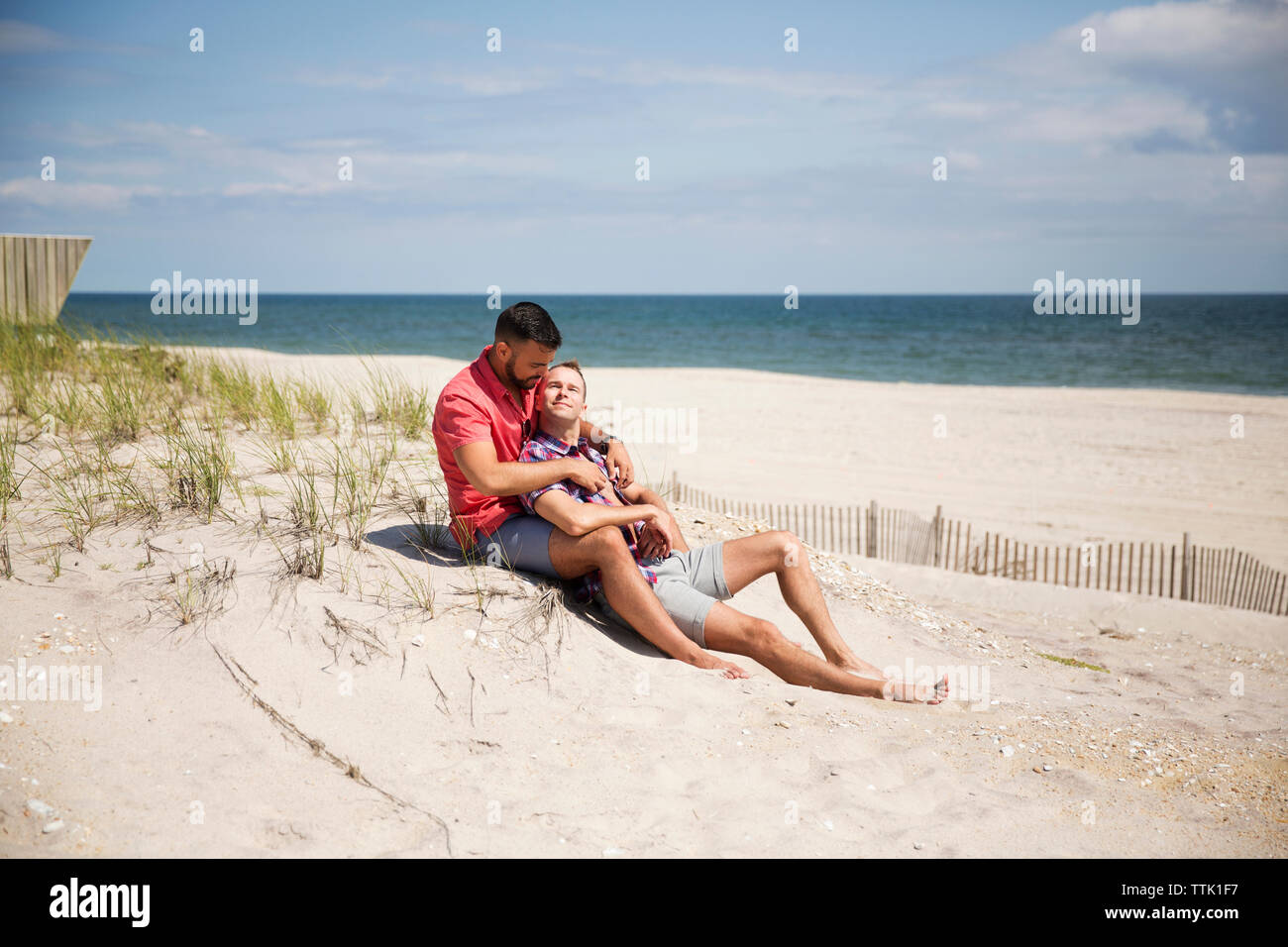Homosexuelle Paare ausruhen am Strand gegen Sky Stockfoto