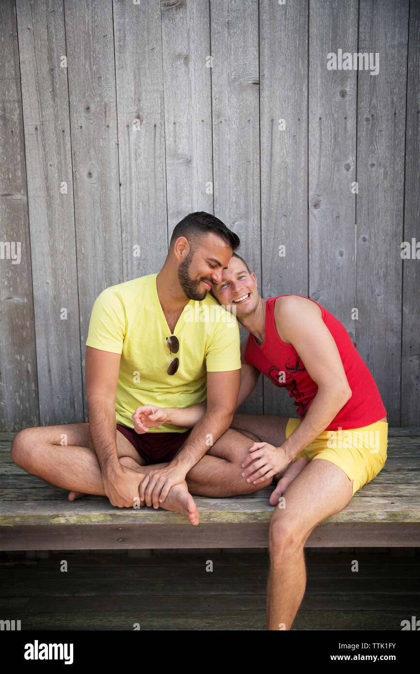 Glücklich homosexuelle Paare sitzen auf holzbank Resort Stockfoto